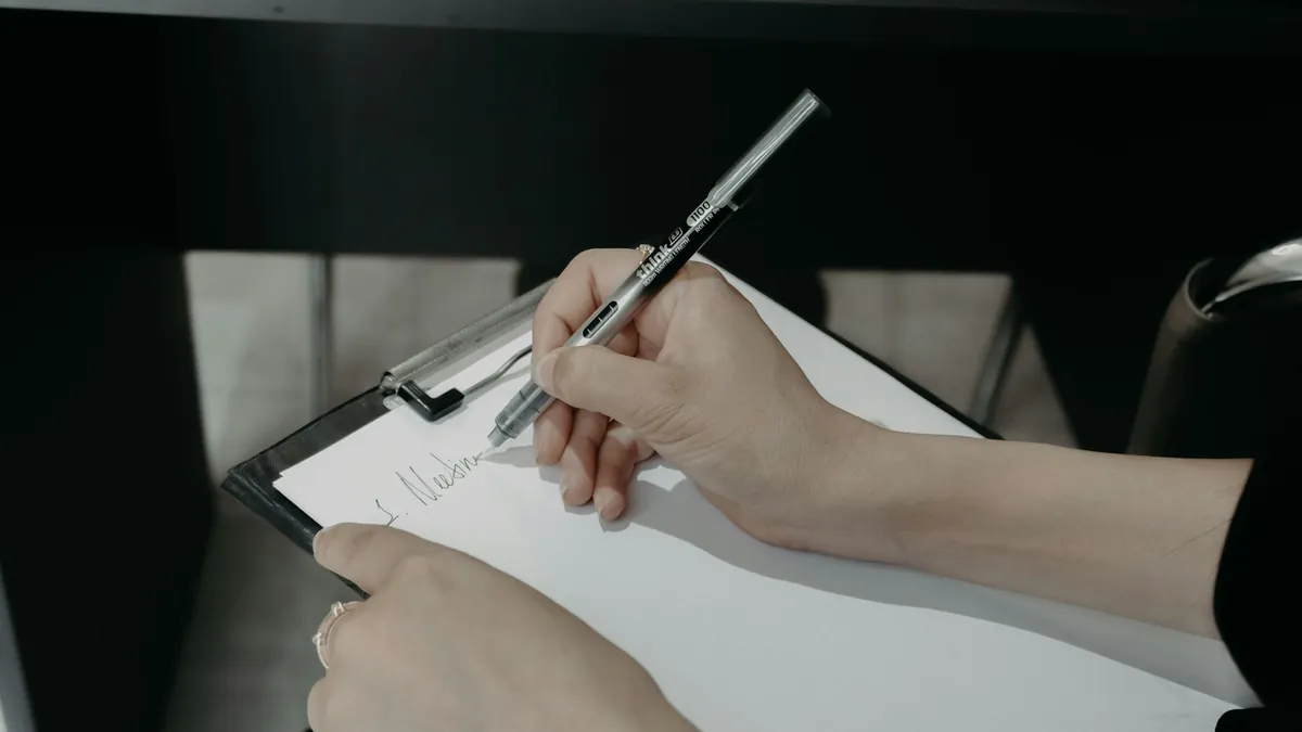 クリップボードの用紙にペンで書き込む手元