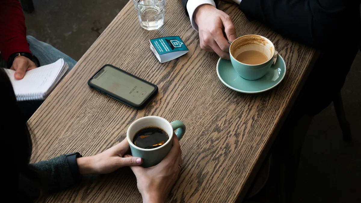 取材中のテーブル。コーヒーカップとメモ帳が置かれている