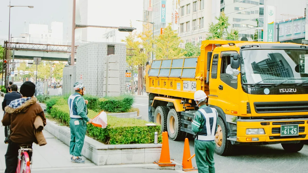 道路脇の工事現場で作業する作業員とダンプトラック